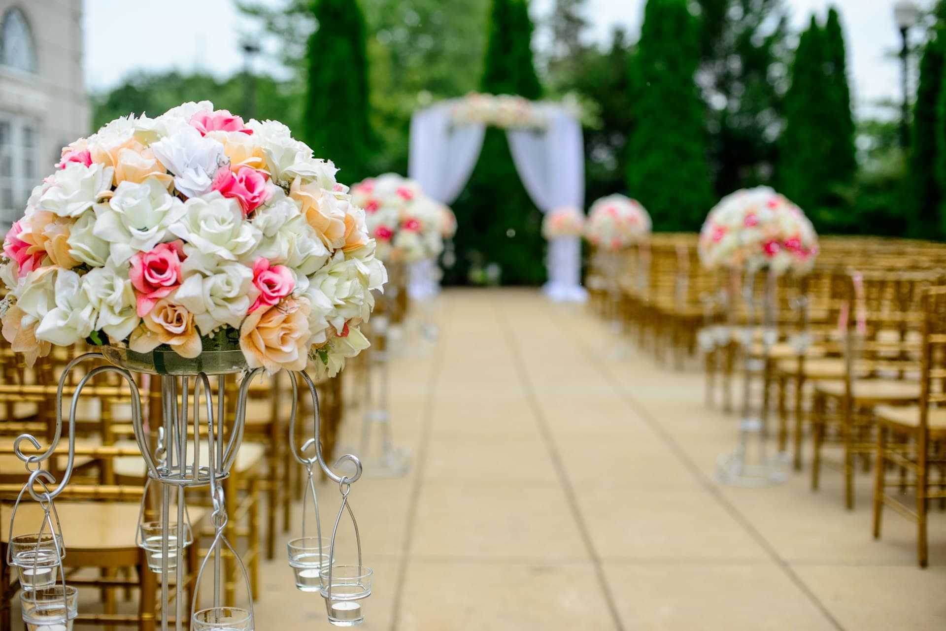 Outdoor ceremony aisle lined with chairs and floral arrangements